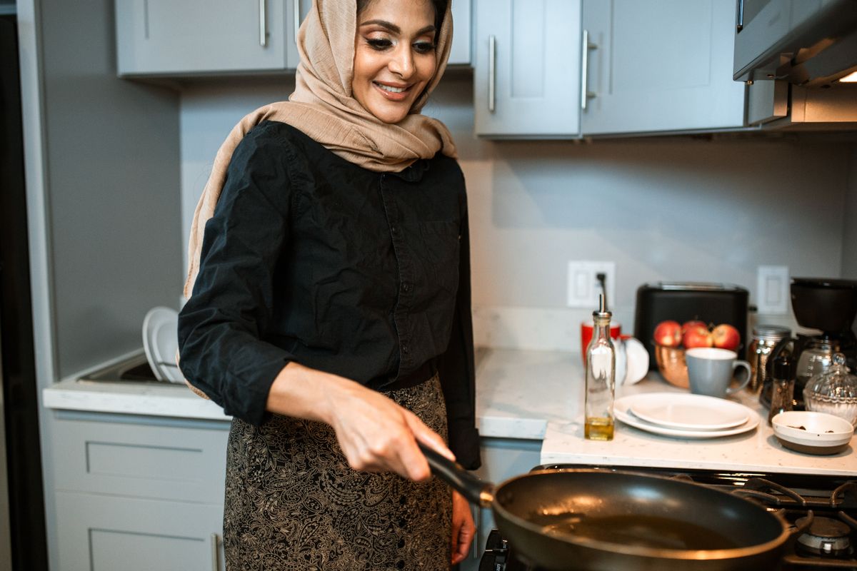 Mulher sorrindo enquanto cozinha na cozinha de casa